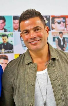 a man standing in front of a wall with posters on it's sides and smiling at the camera