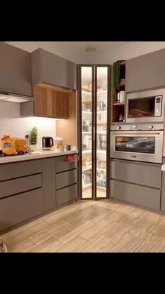 a kitchen with wooden floors and stainless steel appliances in the center, along with an open refrigerator