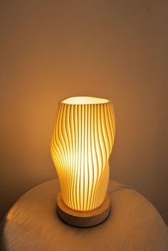 a light that is sitting on top of a table next to a lamp shade in the shape of a vase