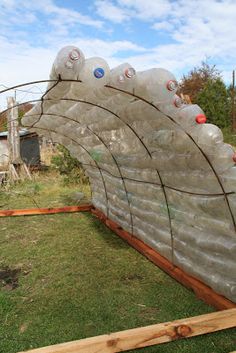 a large rock structure made out of plastic bottles in the grass with a fence around it