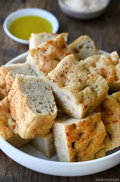 small pieces of bread sitting on top of a white plate next to some dipping sauce