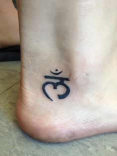 a person with a tattoo on their foot that has the symbol om in black ink