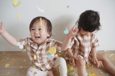 two young children sitting on the floor with confetti falling from their mouths and hands