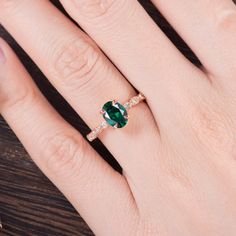 a woman's hand with an emerald and diamond ring