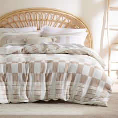 a wicker headboard with pillows and blankets on it in front of a bed