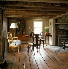 a living room with wooden floors and a fire place next to a table that has chairs on it