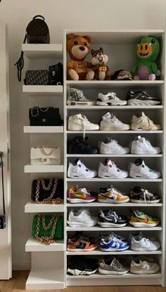 a closet filled with lots of different types of shoes and purses on top of white shelves