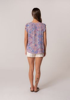 A lightweight summer blouse in a pink and blue floral print. Floral print Metallic clip dot details Relaxed fit Short ruffle sleeve Split v-neckline Women's summer top Feminine and laid back, our ruffle sleeve blouse is designed in a classic bohemian floral print. The perfect warm weather top for summer. We love to pair it with casual cut-off denim shorts. Model is 5'9, wearing a size S.Style: I-14093W-SHO-TL Feminine Multicolor Ruffle Sleeve Tops, Short Sleeve Cotton T-shirt With Ruffles, Cotton Ruffled Short Sleeve T-shirt, V-neck Rayon Top With Ruffles, Bohemian V-neck Top With Ruffle Hem, Ruffle Sleeve Blouse, Bohemian Tops, Bohemian Floral, Womens Tops Summer