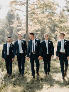 a group of men standing next to each other in the grass with trees behind them