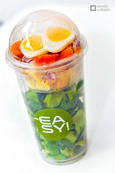 a plastic cup filled with salad and an egg