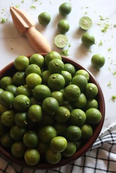 a bowl filled with limes next to a cutting board