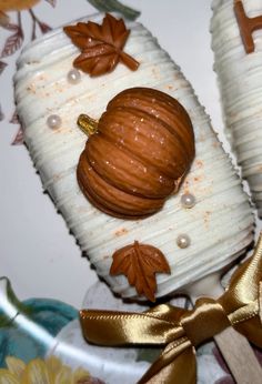 two pumpkin shaped cookies sitting on top of a plate next to a gold ribbon and bow