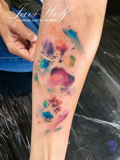 a person's leg with watercolor paint on it and a dog paw tattoo