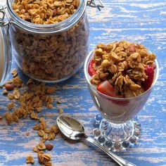 two glass bowls filled with granola and strawberries on top of a blue table