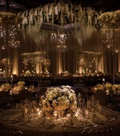 an elegant wedding reception with chandeliers and flowers on the tables at night time