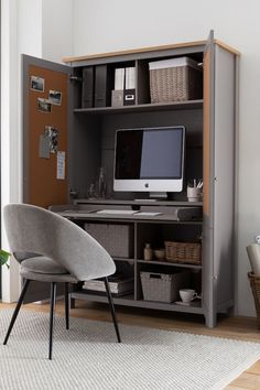 a computer desk with a monitor, keyboard and chair in front of an open bookcase