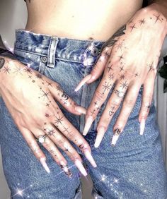 a woman with tattoos on her arms and hands is wearing blue denims, holding onto her stomach