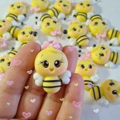 a hand holding a tiny yellow and black bee figurine with lots of hearts around it