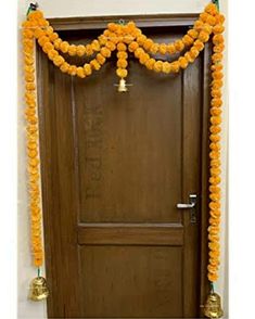 a door decorated with orange flowers and bells for an entrance to a house or office