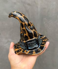 a hand holding a ceramic animal hat