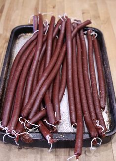 some very long red carrots sitting in a pan on a wooden table with the words, venison snack sticks