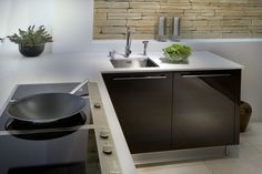 a modern kitchen with stainless steel appliances and white counter tops, along with a stone wall behind the sink