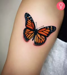 an orange and black butterfly tattoo on the arm