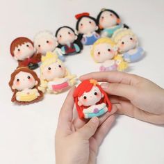 a hand holding a tiny doll surrounded by small dolls