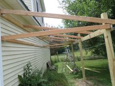 a wooden structure in the grass next to a house