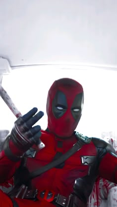 a man dressed as deadpool holding a baseball bat in his right hand and pointing to the left