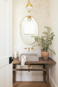 a bathroom with a sink, mirror and potted plant