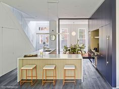 a kitchen with three stools next to an island in the middle of the room