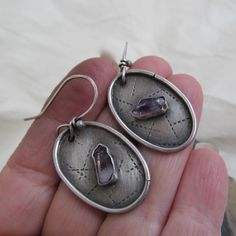 Raw Amethyst Dangle Earrings Rustic Purple Gemstone Hoop Earrings Silver Dangling Earring: Beautiful raw Amethyst points have been captured in hand constructed sterling silver settings.The oval backings have been stamped with a linear pattern and darkened. Each earring is slightly different from the other. They measure about 1 3/4 inches in total length. Truly one-of-a-kind and handmade by me. Enter my shop: https://www.etsy.com/shop/artdi Join me on Facebook: https://www.facebook.com/Artdi-Dian Purple Metal Drop Earrings, Purple Teardrop Metal Earrings, Purple Pierced Metal Jewelry, Purple Metal Pierced Jewelry, Purple Drop Crystal Earrings, Purple Teardrop Metal Jewelry, Unique Amethyst Jewelry With Matching Earrings, Silver Amethyst Drop Crystal Earrings, Unique Amethyst Teardrop Earrings