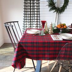 the table is set for christmas dinner with plates, silverware and oranges on it