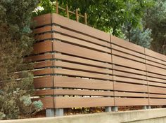 a wooden bench sitting on the side of a road in front of trees and bushes