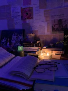 an open book sitting on top of a desk next to a lit candle