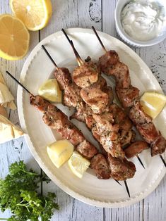 chicken skewers with lemons and parsley on a white plate