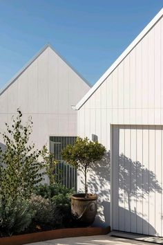 two white buildings with trees in front of them and a planter on the side