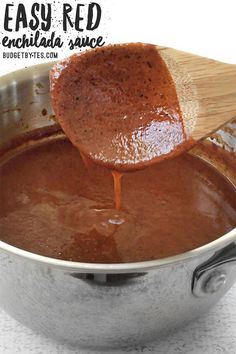 a wooden spoon is being used to stir sauce in a pot with the words easy red enchilada sauce on it