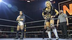 two female wrestlers are standing in the ring