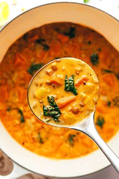 a spoon full of soup with carrots and spinach