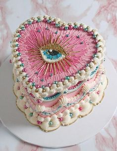 a pink and white cake with an eye on it's top sitting on a plate