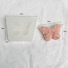 a butterfly shaped object sitting on top of a white sheet next to a piece of paper