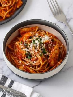 two bowls of pasta with sauce and parmesan cheese on the side next to silverware