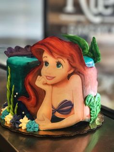 the little mermaid cake is made to look like it's sitting on a table