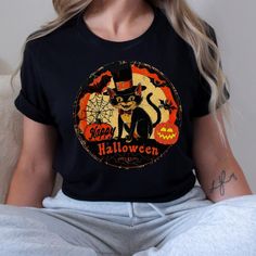 Vintage Retro Halloween Cat t shirt, Nostalgic retro gift for her, Halloween Kitty Cat Lover gift tee for mom 🌟 **Step into the past with our Retro Halloween Cat Unisex Jersey Tee 🌟 Embrace the charm of yesteryear with our  Retro Halloween Cat Unisex Jersey Short Sleeve Tee. This classic tee is not just a piece of clothing; it's a nostalgic journey wrapped in soft cotton and adorned with adorable vintage baby animals. Perfect for all ages, this tee fits like a well-loved favorite and will make you fall in love over and over again. ✨ **Quality You Can Feel Made with 100% Airlume combed and ring-spun cotton, our lightweight fabric (4.2 oz/yd² or 142 g/m²) is a dream to wear. The breathable material is easy to layer, making it ideal for both active and leisure wear. The ribbed knit collars, Novelty Black T-shirt As A Gift, Novelty Black T-shirt As Gift, Novelty Black T-shirt For Gift, Halloween Black T-shirt With Cat Design, Retro Halloween T-shirt With Character Print, Black Halloween T-shirt With Cat Design, Halloween Graphic Print Top As Gift, Vintage Black Top Gift, Black Vintage Top Gift