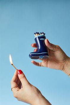 a woman holding a toothbrush in one hand and a match lighter in the other