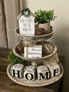 three tiered trays with plants and signs on them sitting on a wooden table