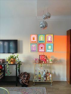 a living room with art on the wall and various drinks in bottles sitting on a shelf