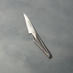 a knife on a gray surface with the handle still attached to it's blade